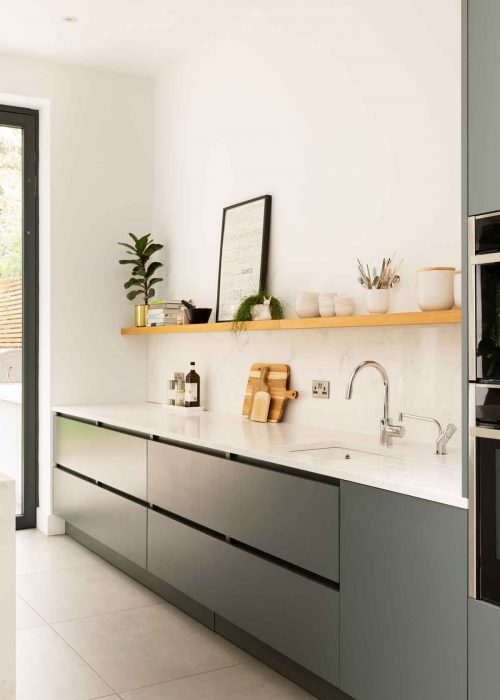 Portrait photo of dark grey kitchen cabinets and white worktop and open shelving above